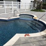 Gray pavers with white coping and pebble finish