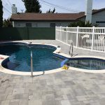 Gray pavers with white coping and pebble finish