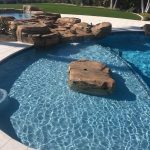baja bench with center rock and rock werk waterflow from spa to pool